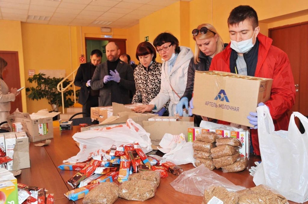 Рука передает хлеб другому человеку, символизируя продуктовую помощь малообеспеченным